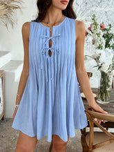 Model in light blue Allurista™ mini dress standing under a floral arch at a romantic outdoor wedding ceremony.