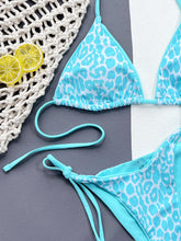 Close-up flat lay detail of aqua leopard print tie side bikini set showing halter neck and side tie string detail