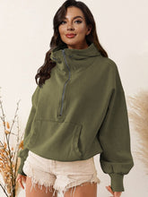 A model wearing the army green color Nuvella Zip-Up Dropped Shoulder Hoodie paired with distressed tan denim shorts.