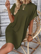 Woman seated at a coffee shop wearing Army Green Rahluna Mini Tee Dress paired with tan mules and a crossbody bag.
