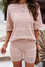A model wearing the Blush Pink Aurelyss Eyelet Round Neck Top and Shorts Set paired with jewelry and a tan woven handbag.