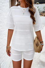 A model wearing the White Aurelyss Eyelet Round Neck Top and Shorts Set paired with jewelry and a tan woven handbag
