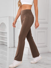 Model walking outdoors wearing AuriCore Flexion Brown Pants and sneakers.