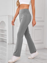 Model walking outdoors wearing AuriCore Flexion Gray Pants and sneakers.