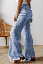 A female posing from the side wearing light medium blue Avaris DriftCrest Raw Hem Bootcut Denim Jeans paired with a white blouse, jewelry, a brown shoulder bag, and brown multicolored loafers.