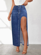 Close-up of Averlynn Curve Skirt in dark blue styled with white top and heels highlighting curved slit and washed denim texture