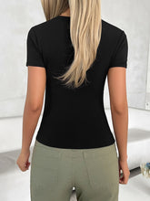 Back view of a model in a dark gray scoop neck short sleeve T-shirt, paired with relaxed black pants.