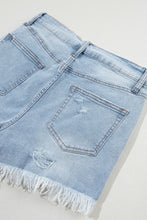 Flat lay of light blue distressed high waist denim shorts, back view featuring pockets and raw hemline.