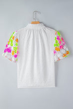 Back view of LustruBloom Blouse showcasing sequin floral half sleeves and ruched mock neckline, on a hanger.
