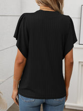 Back view of the Round Neck Flutter Sleeve T-Shirt in black, showing relaxed fit and flutter sleeve detail, paired with denim shorts.