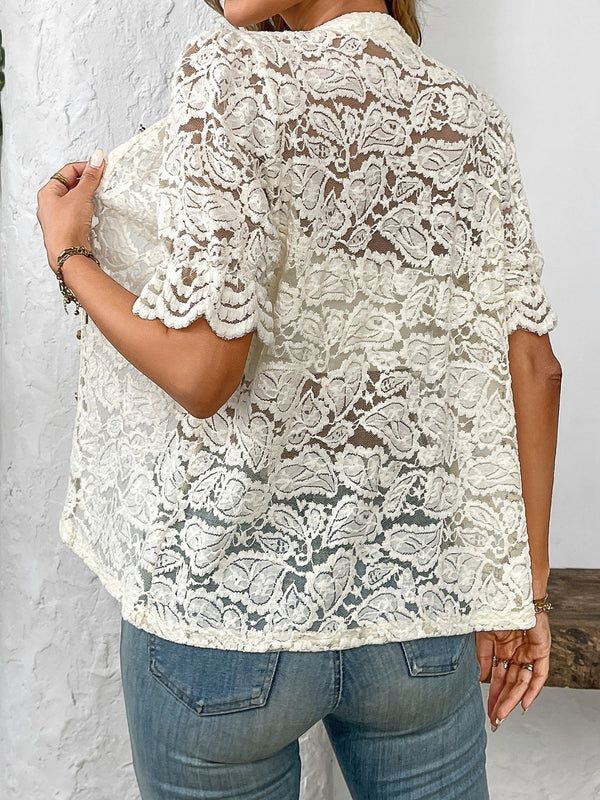 Back view of model showcasing the intricate lace detailing and airy fit of the cream button-down lace shirt paired with neutral trousers.