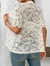 Back view of model showcasing the intricate lace detailing and airy fit of the cream button-down lace shirt paired with neutral trousers.