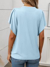 Back view of the Round Neck Flutter Sleeve T-Shirt in light blue, showing relaxed fit and flutter sleeve detail, paired with denim shorts.