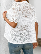 Back view of model showcasing the intricate lace detailing and airy fit of the white button-down lace shirt paired with neutral trousers.