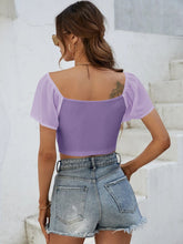 Back view of Glowflutter Crop Top showing soft fabric and flutter sleeve flow, worn by model in pink purple.