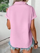 Back view of model showcasing the lightweight, relaxed fit of the pink purple pleated collared neck short sleeve blouse, paired with white trousers.