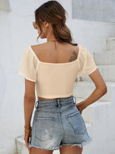 Back view of Glowflutter Crop Top showing soft fabric and flutter sleeve flow, worn by model in tan.