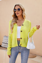Woman sipping coffee at an outdoor café in the Solavelle V-Neck Cardigan in banana yellow, paired with white trousers and sunglasses for a fresh, chic vibe.