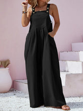 Model in black overalls at a rooftop gathering, styled with statement sunglasses and a bold clutch.