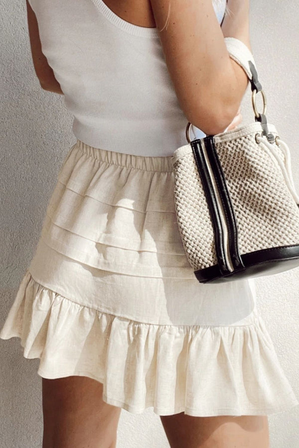 Back view of beige Elunari Ruffled Hem Mini Skirt styled with a white top and cream shoulder bag