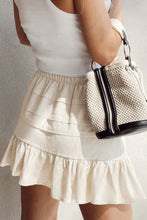 Back view of beige Elunari Ruffled Hem Mini Skirt styled with a white top and cream shoulder bag