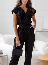 Model posing in black Bellavana Grandeur jumpsuit with statement earrings.