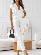 Close-up of model in white Bellavana Grandeur jumpsuit, capturing soft cap sleeves, surplice neckline, and polished tie waist accent.