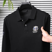 Close-up front view of black Equestrian Crest Designer Polo on hanger showing embroidery, buttons, and flip color-contrast collar.