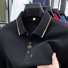 Close-up front view of black Royale Crest Fleur de Lis Polo showing embroidered placket detail.