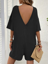 Back view of black romper showing open V-back cut.
