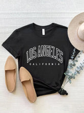 CaliVista Tee in black paired with straw hat and tan loafers in flat lay, styled for casual summer outfit inspiration.