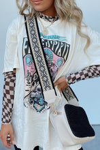 Model posing in the black ChicGrid checkered mock neck blouse paired with distressed leggings, layered tee, long wide straped purse, and
jewelry, styled for a chic casual look.