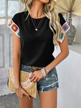 Model styled in black CrochetCharm Top with shorts, sandals, a tan straw purse, and accessories for a complete look.