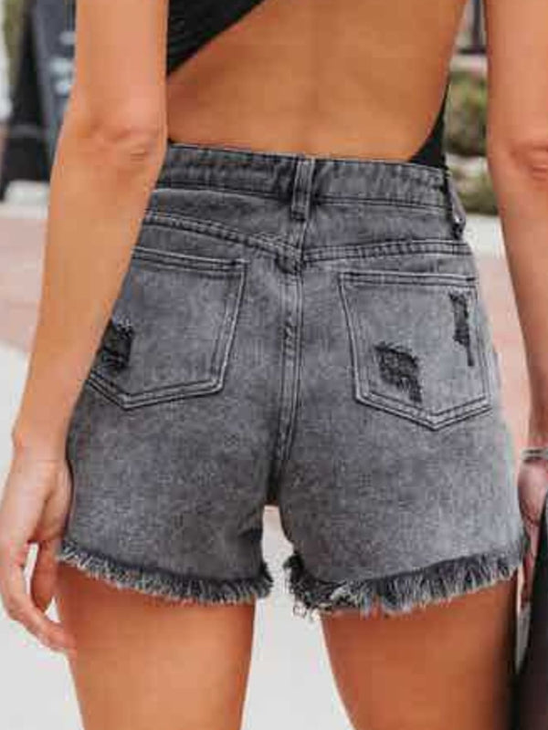 A model showcasing the back of black Untamed Calamity Distressed Fringe Denim Shorts.