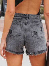 A model showcasing the back of black Untamed Calamity Distressed Fringe Denim Shorts.