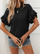 Model wearing Contrast Round Neck Short Sleeve Blouse in Black, paired with denim jeans, standing against a neutral backdrop