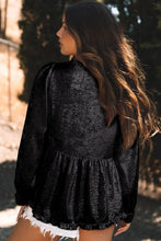 Back view of Glimmerelle™ Blouse in Black, highlighting the ruffled peplum hem, accessorized with gold jewelry and strappy heels.