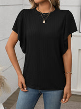 Model in a black Round Neck Flutter Sleeve T-Shirt, styled with wide-leg linen pants and a straw tote at a sunny garden brunch.