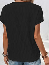 A woman showcasing the back of a black Full Size Ruched Wavy Textured Round Neck Short Sleeve T-Shirt riding the metrorail in Miami.