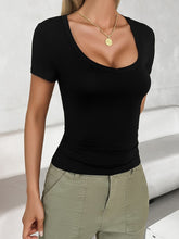 Front view of a model in a black scoop neck short sleeve T-shirt, paired with relaxed black pants.