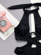 Close-up flat lay of black cutout halter neck one-piece swimwear showcasing fabric texture and underwire detail
