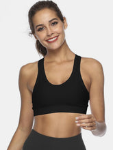Woman wearing black active tank in yoga studio stretch pose.