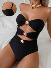 Relaxed close-up of model wearing black cutout sweetheart neck one-piece swimsuit showing gold starfish accent and cutout details