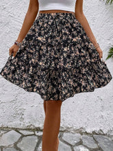 Model posing in black Florévyn Floral Print Midi Skirt featuring frill tiers and ruffled hem