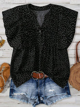 Front view of EverDot Flutter Top in black polka dot with flutter sleeves paired with earrings, belt, brown sandals, and straw handbag in a flat lay photo.