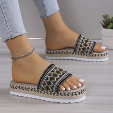 a model wearing a black pair of Geometric Weave Platform Sandals