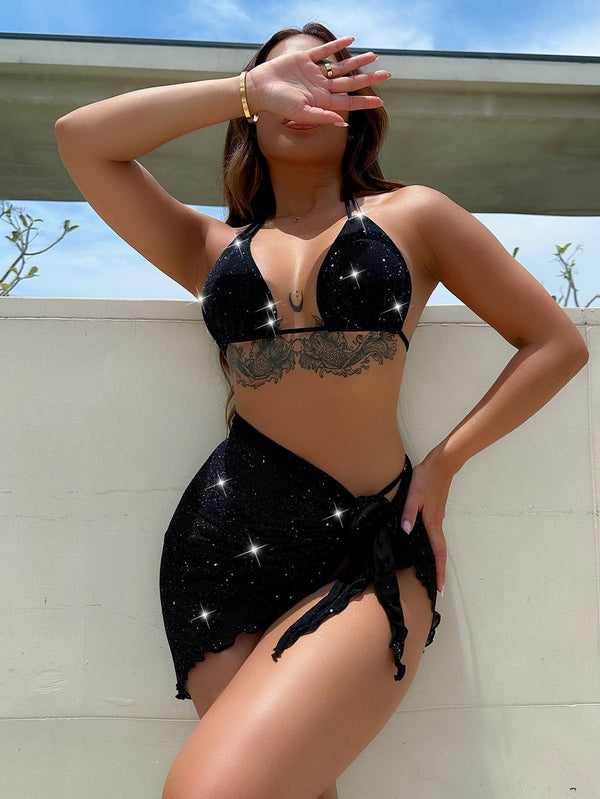 Model wearing black glitter halter neck backless three-piece swim set front view at resort poolside with silver sparkles