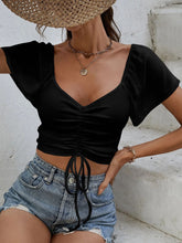 Close-up of adjustable front-center drawstring on Glowflutter Crop Top in black, highlighting stretch fabric and ruching.