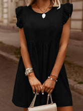 Model in black Sylvenza Denim Dress styled with tan and gold handbag and accessories standing on urban city street.