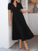 Close-up of black Velunira dress textured fabric and decorative buttons.